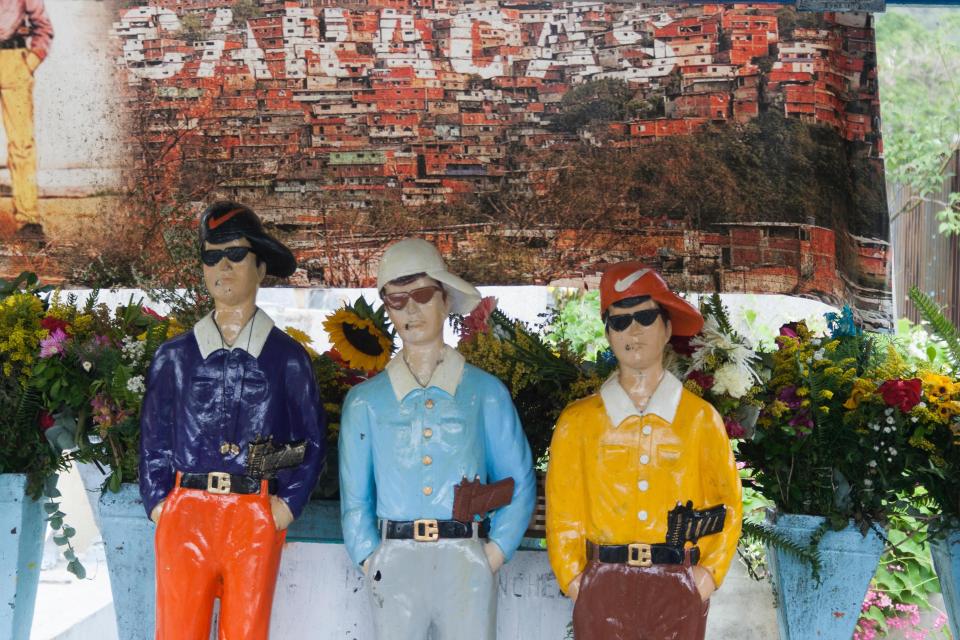  The shrines all feature men smoking cigarettes with guns tucked into their belts