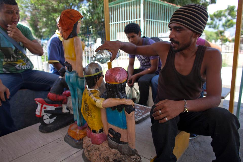  Ivan, a believer, makes an offering as he pours alcohol over the statues of Ismael and Elizabeth who was the girlfriend of Ismael