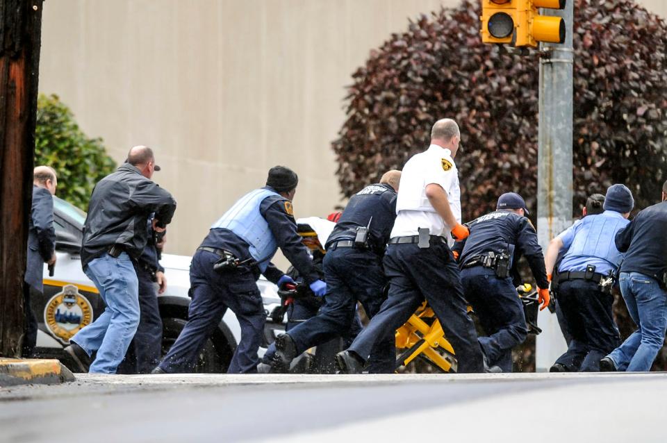  Law enforcement run with a person on a stretcher at the scene where multiple people were shot