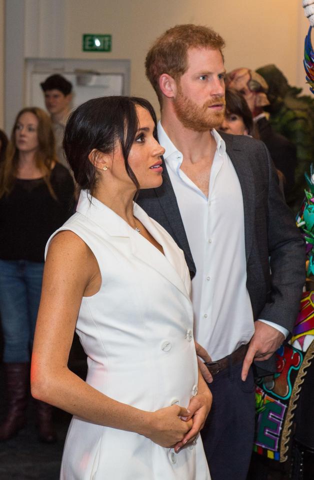  Meghan cradles her baby bump while visitng Courtenay Creative on day two of the royal couple's tour of New Zealand