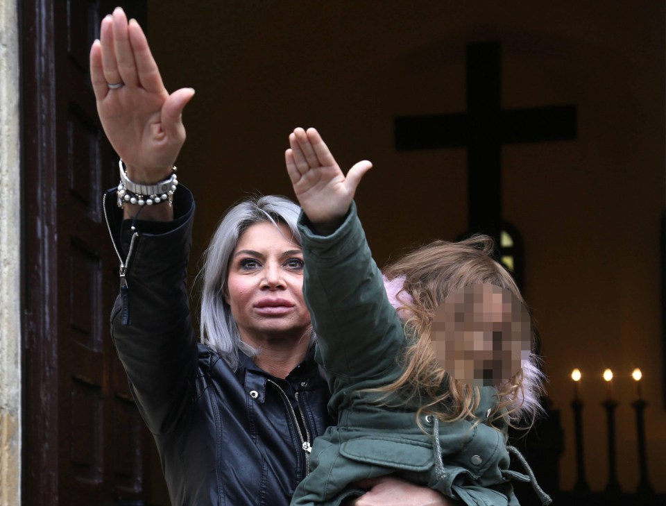 A woman gives a fascist salute while holding a child