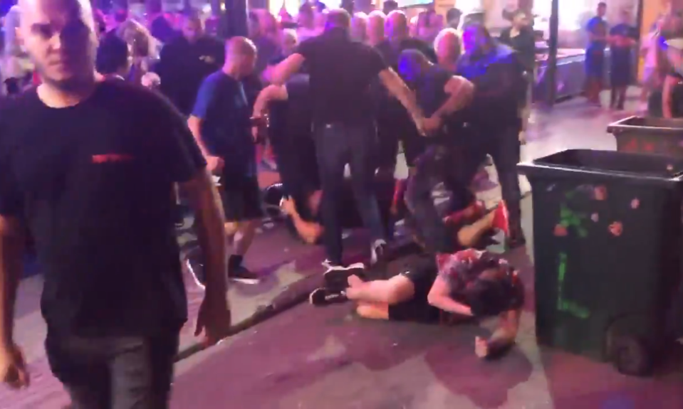  A man holds his head after being sucker-punched by a man in a tee shirt bearing the letters RRPP