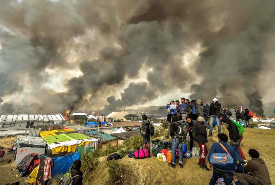  Migrants looking at rising smoke from the Calais Jungle as the camp was being cleared in October 2016