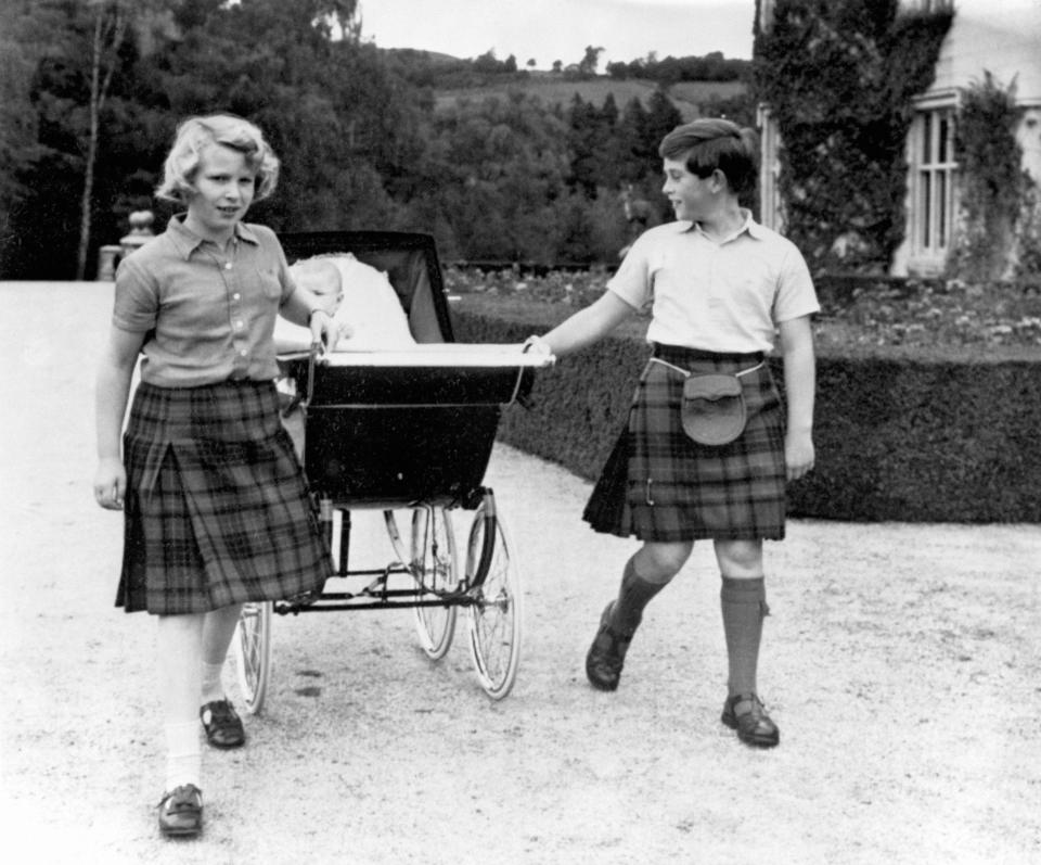  1960: Princess Anne, 10, and Prince Charles, 11, sharing the task of pulling the pram of baby brother Prince Andrew for a walk in the grounds at Balmoral