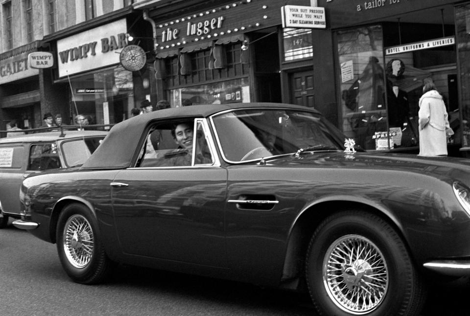  1971: Prince Charles at the wheel of his 5500 Aston Martin DB6 convertible sports car, driving along London's Strand