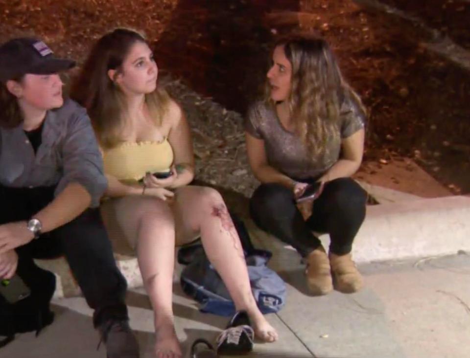  A girl with a bloodied knee sits with friends as police seal off the area