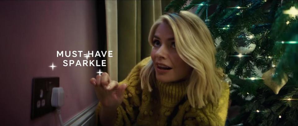  Once Holly plugs in her lights, the advert transports her to a familiar festive realm of Christmas parties and movie screenings