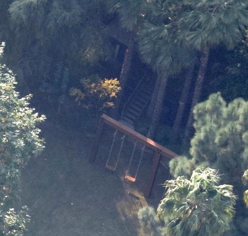  An impressive swing set sits adjacent to the cool treehouse