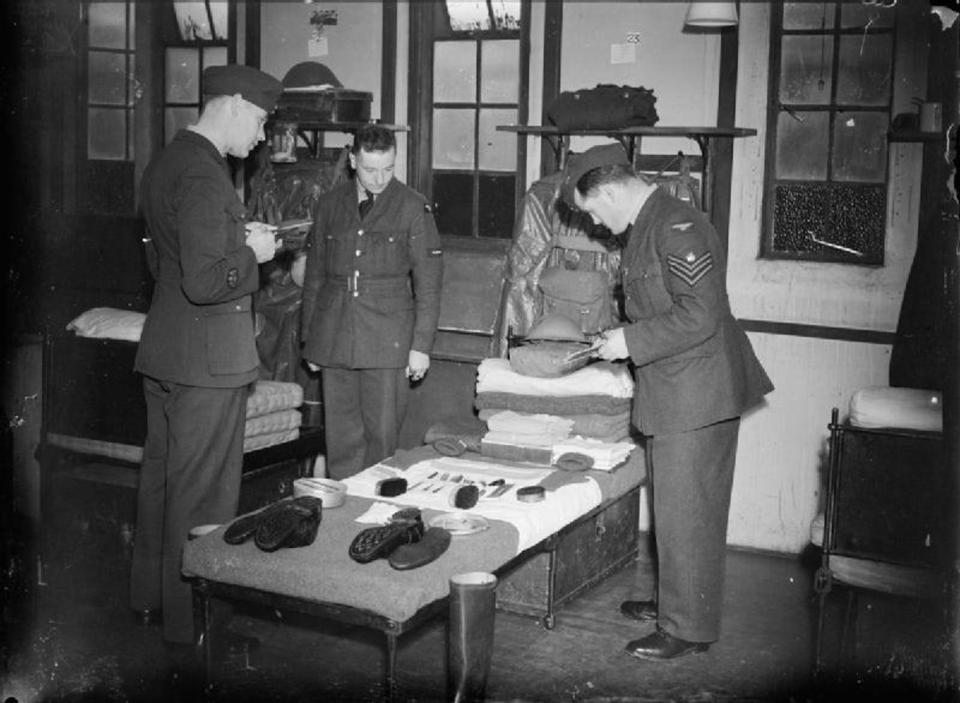  Warrant Officer W Gamblen (left), checking the kit of a newly arrived airman at Hooton Park