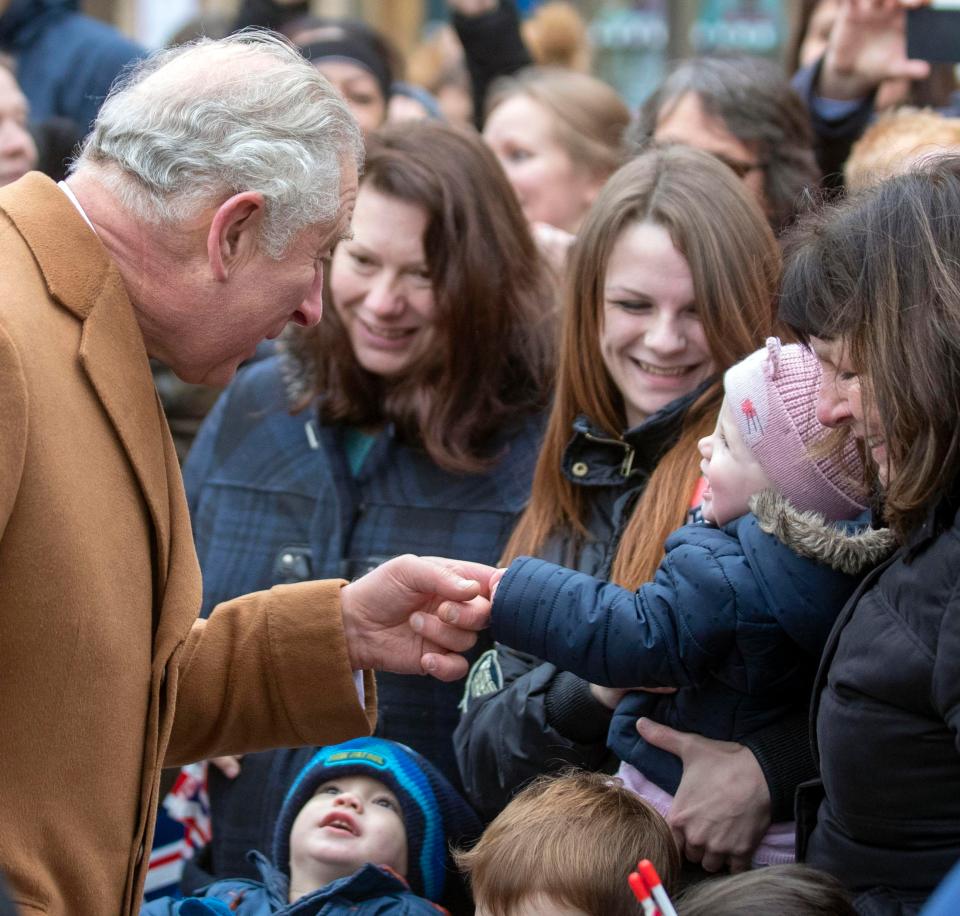  The Prince of Wales shakes hands with a baby during a visit to Ely Market Place