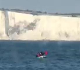  Fisherman Matt Cocker snapped migrants in a dingy waving a red shirt attached to an oar in front of the White Cliffs of Dover in September