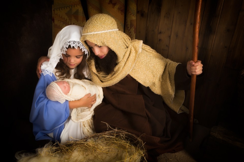  Children depict Mary and Joseph cradling the baby Jesus in Nativity scene