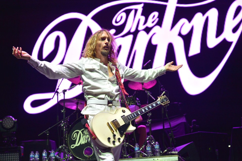 a man playing a guitar in front of a sign that says the kinky