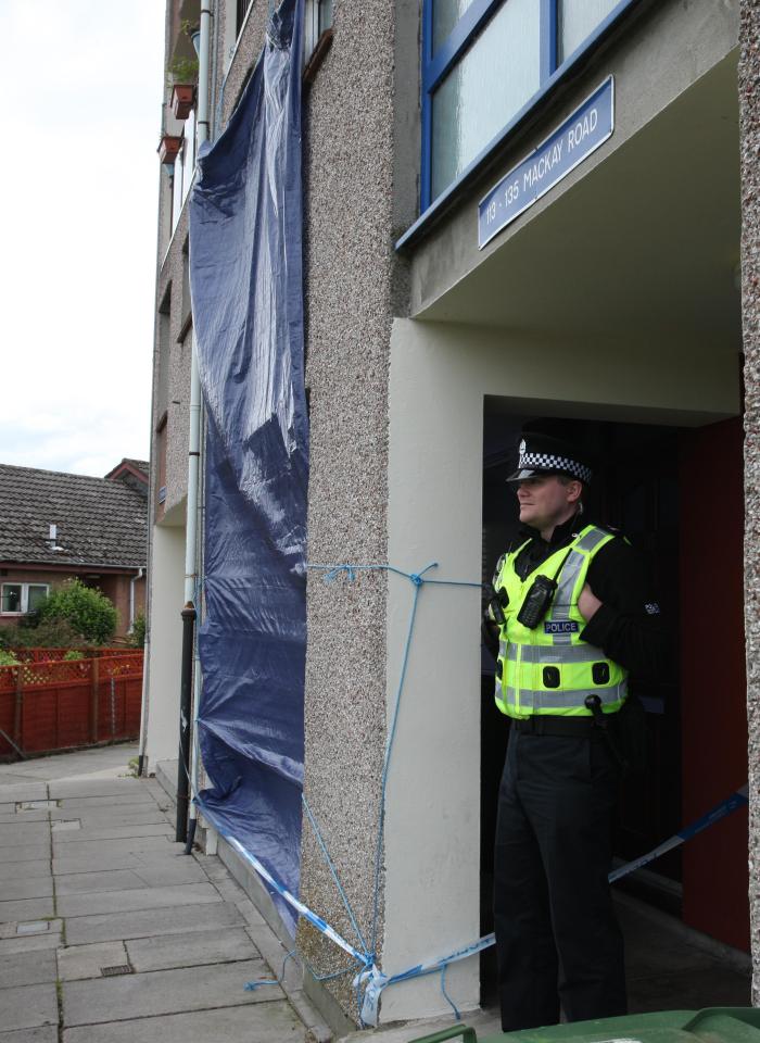  A policeman stands guard outside the flat