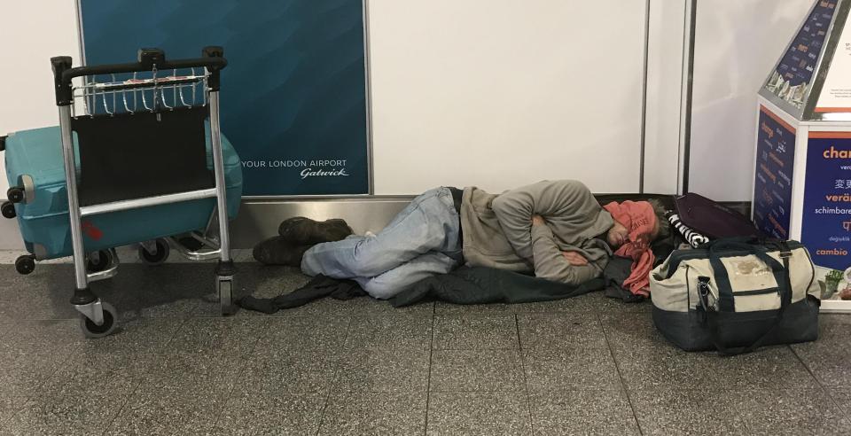  A man bed's down next to his suitcase as he waits for news at Gatwick