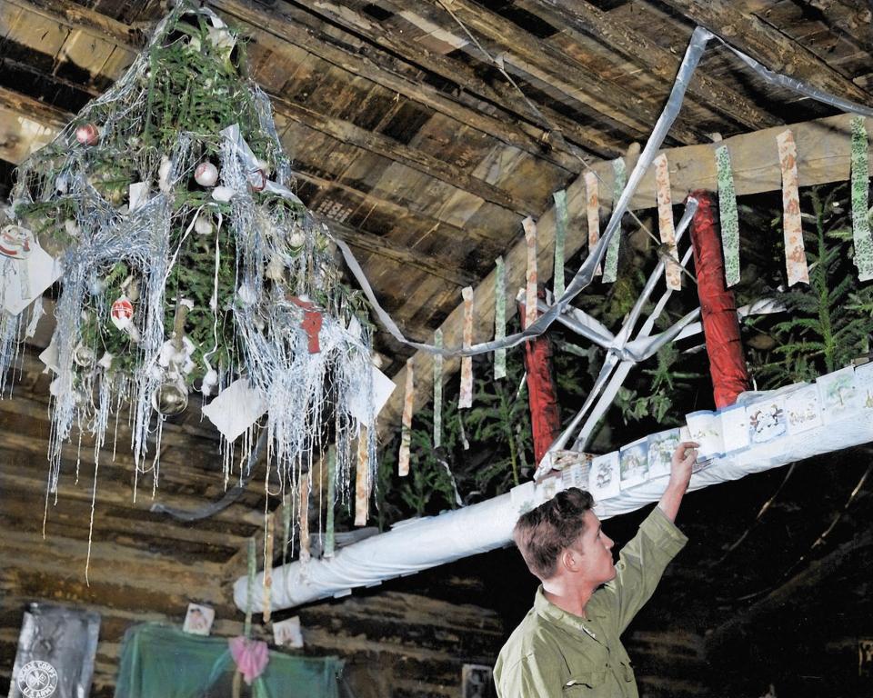  One cabin decorated with a hanging Christmas tree as a soldier reads Christmas cards sent from loved ones