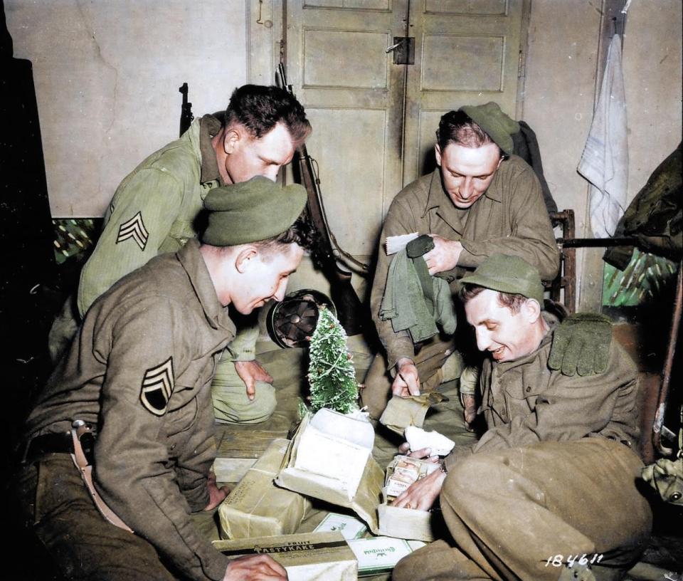  American soldiers sort through mail from their loved ones while surrounding a miniature Christmas tree in 1940