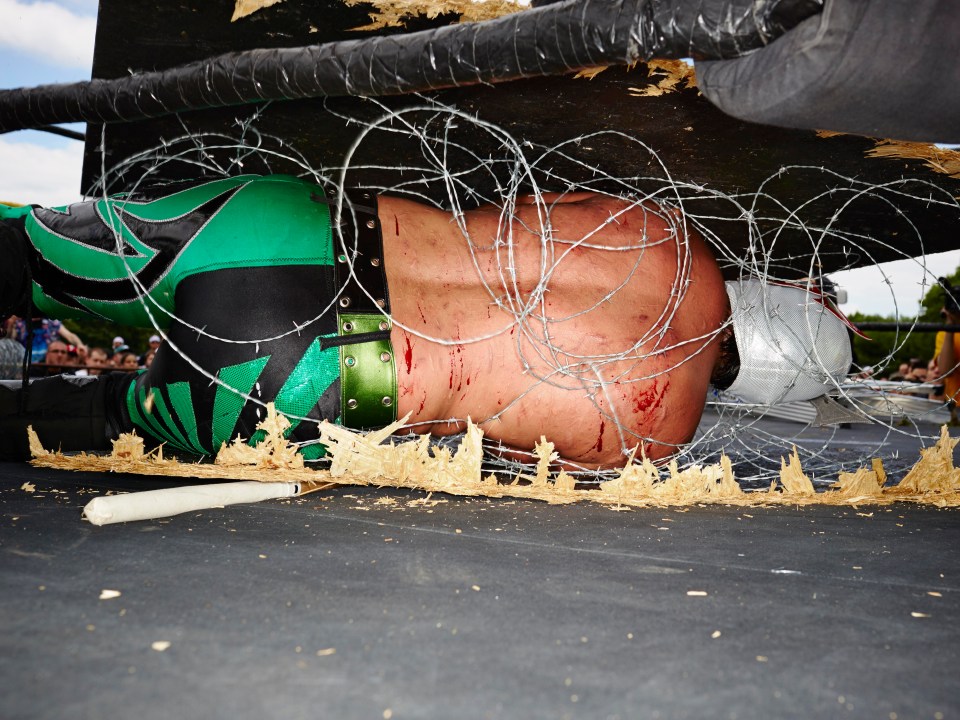 Aero Boy is wrapped in barbed wire after being thrown off a wooden board during a match