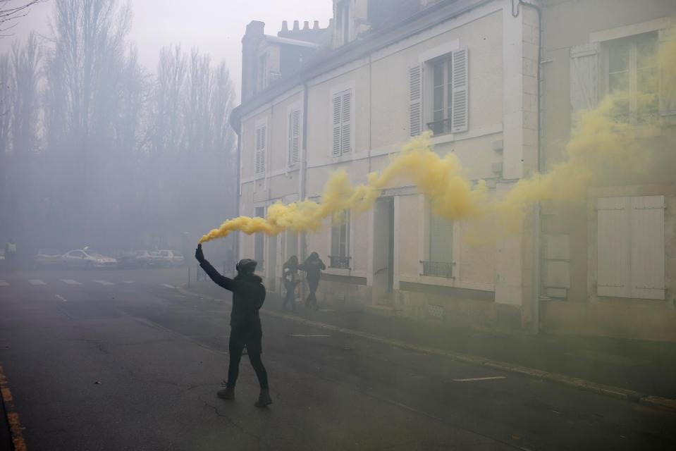  A protester lets off a yellow smoke bomb in the middle of the street as part of the march