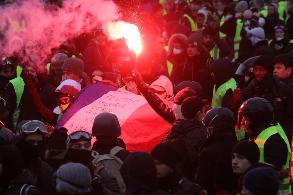  Protesters hold a burning flare and a French flag during an anti-government demonstration in Paris