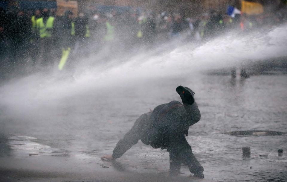  A protester is knocked to the ground by the force of the water canon