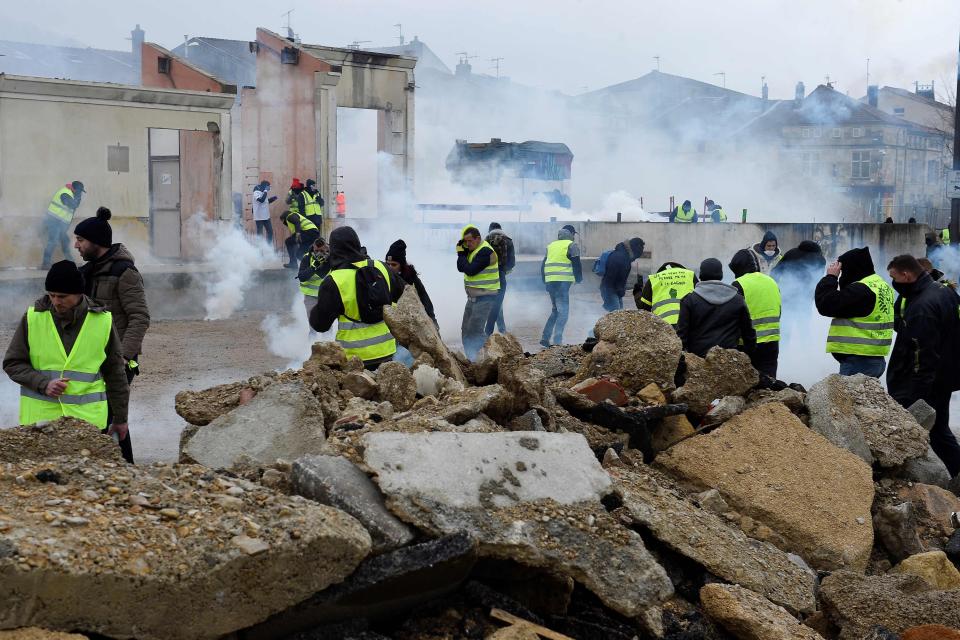  Protesters take cover from tear gas during clashes with police in Paris