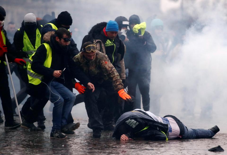  Protesters wearing yellow vests help a person injured by a water cannon