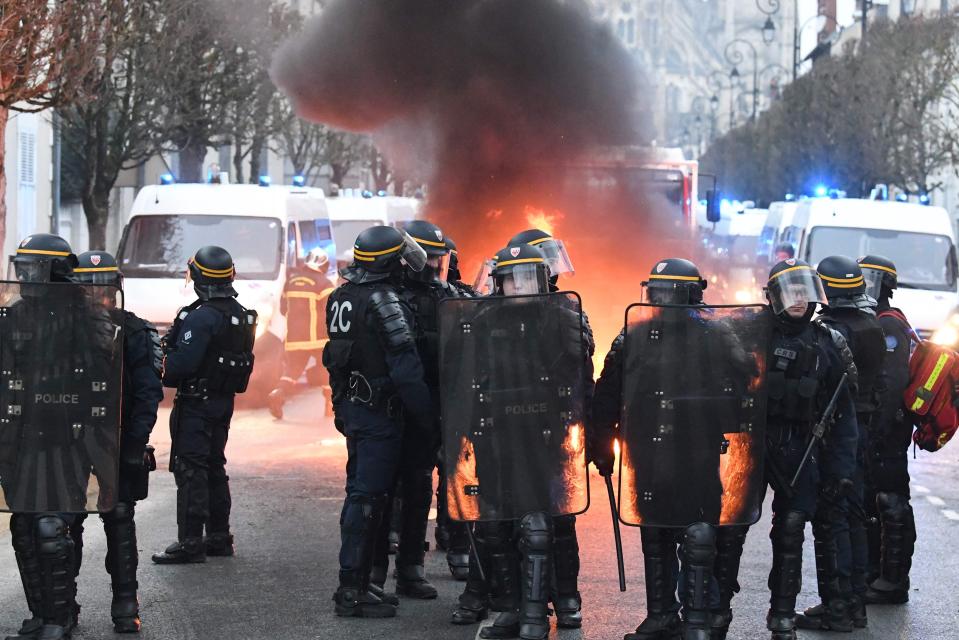  French riot police forces stand in front of a burning barricade