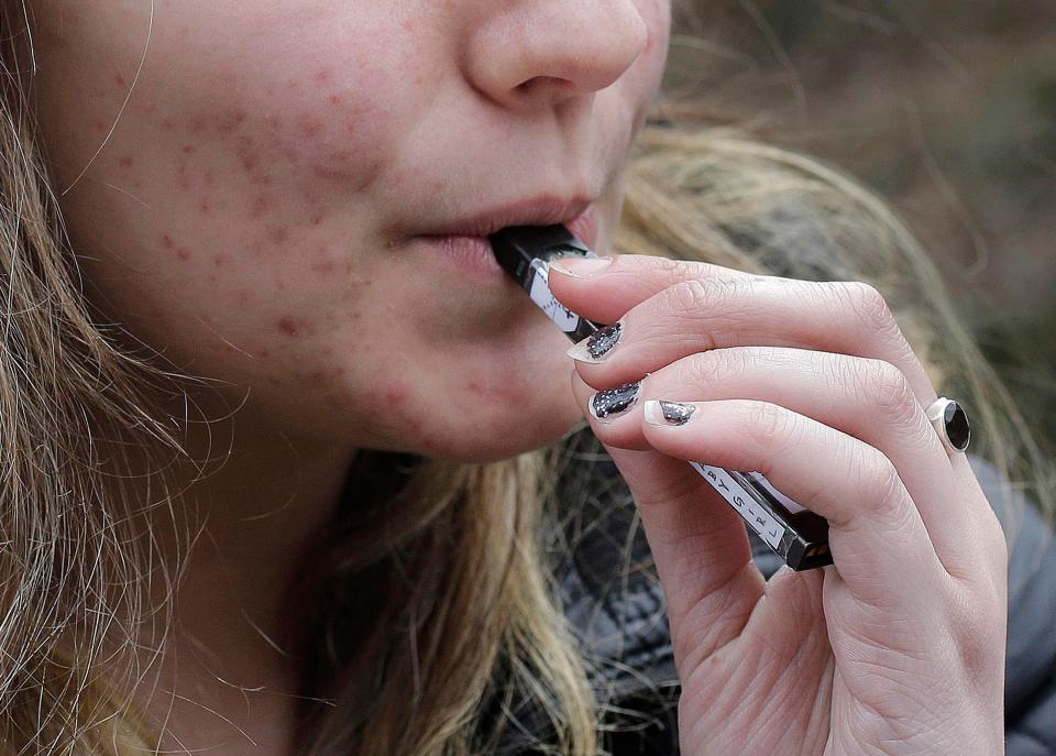 A high school student uses a vaping device near a school campus in Cambridge, Mass