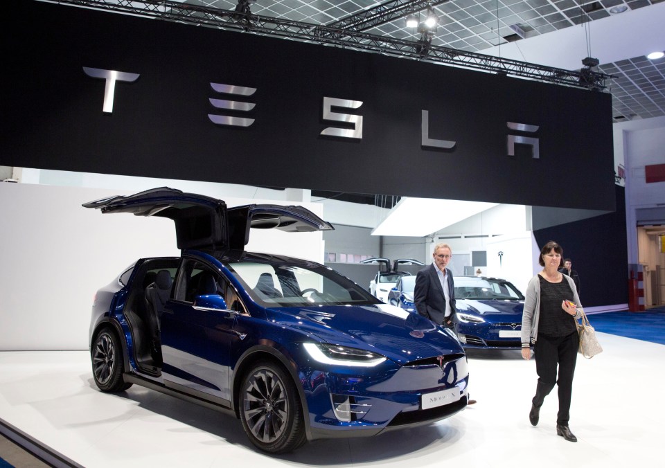 A couple walk next to the new Tesla Model X during the opening of the Brussels Auto Show in Brussels