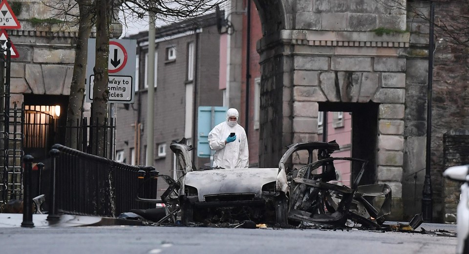 An investigator with the twisted wreckage of the van used in a car bombing in Londonderry