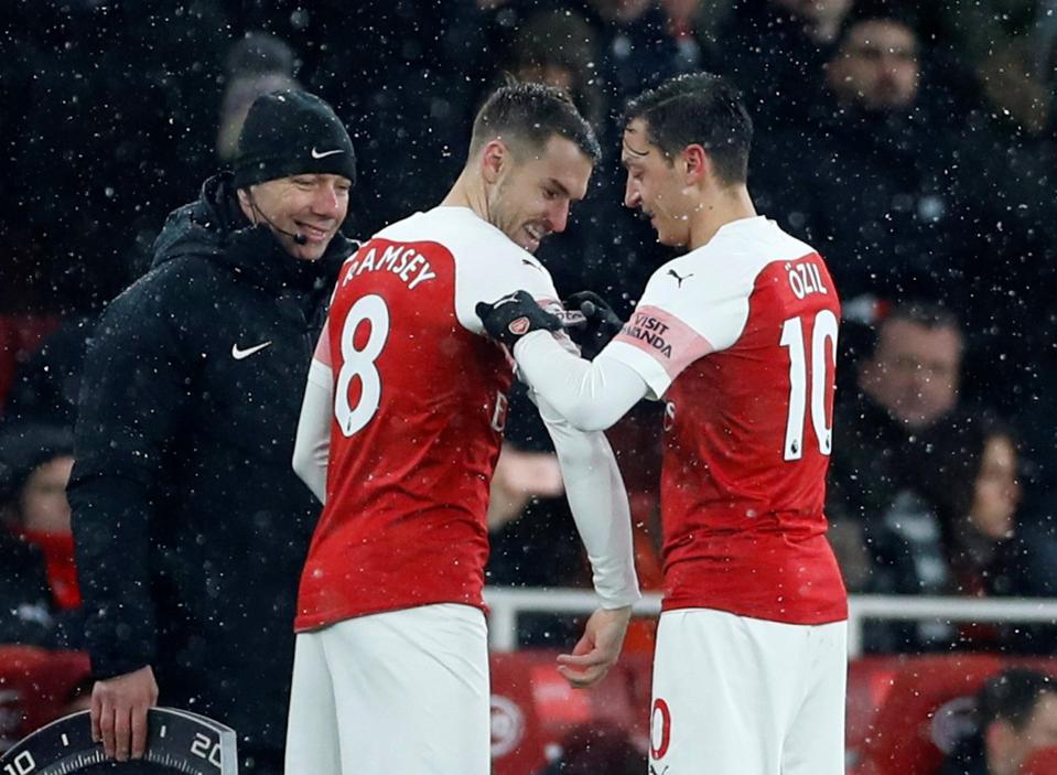  Mesut Ozil hands over the captain's armband to Aaron Ramsey