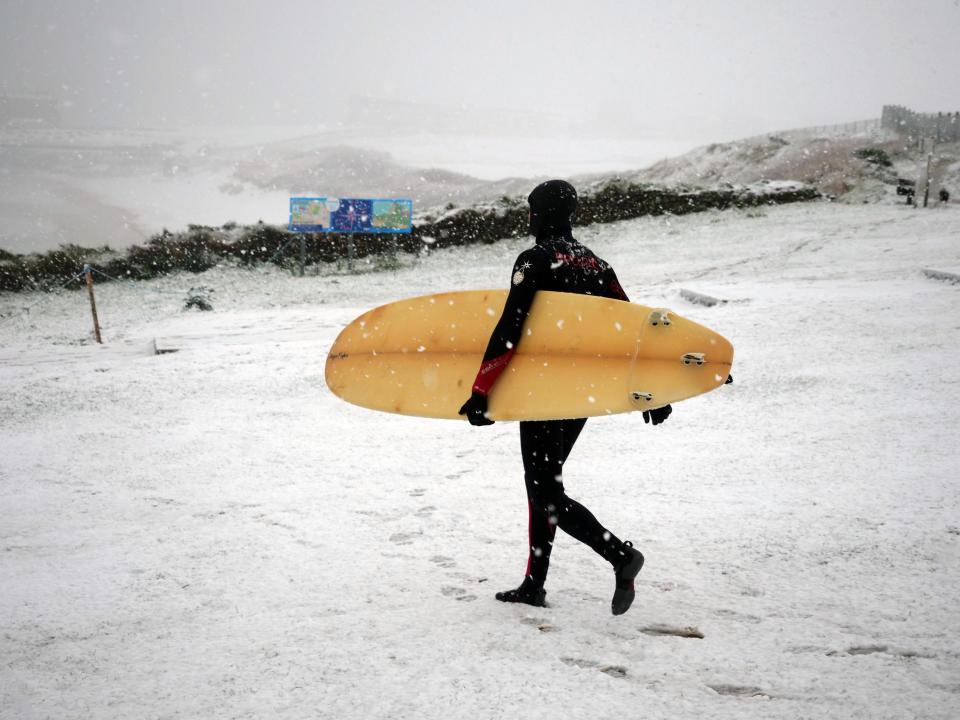  A brave surfer heads out onto the beach in Newquay, Cornwall today