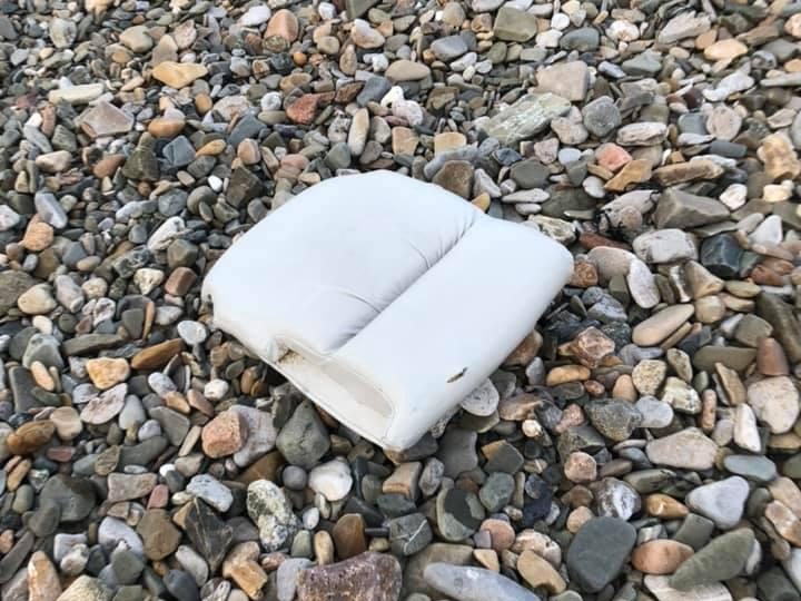  A cushion from the plane seat is left strewn across the pebbles