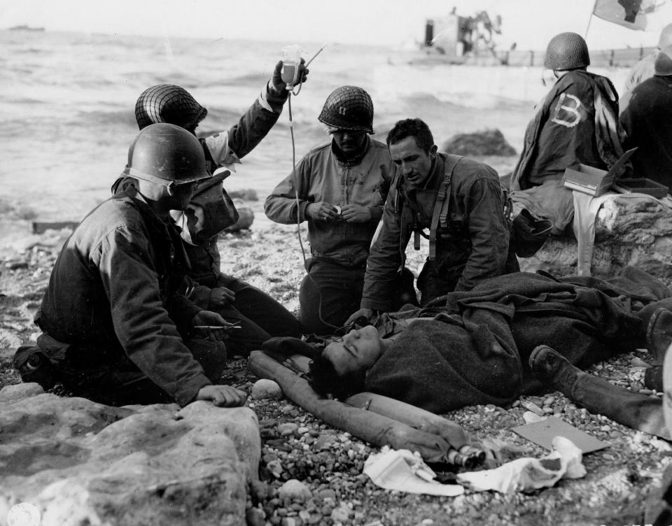  An injured soldier receives blood plasma on the beaches of Normandy