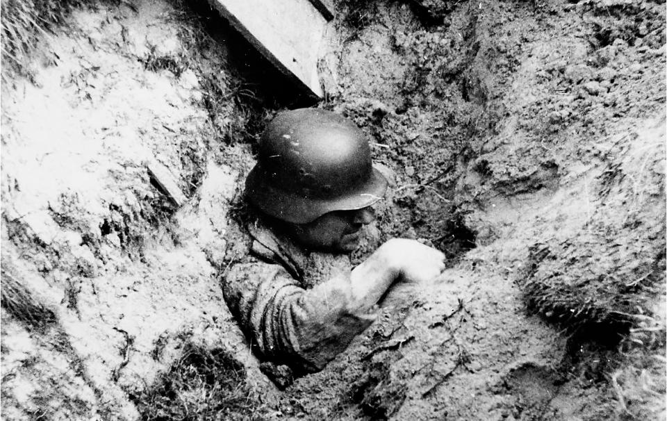  A German soldier lies partially buried after a trench collapsed due to artillery shelling