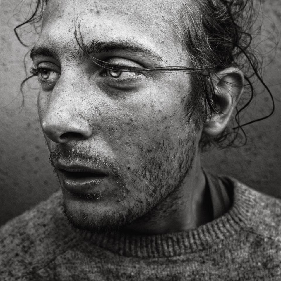 This photograph is a portrait of a young man who has recently been made homeless