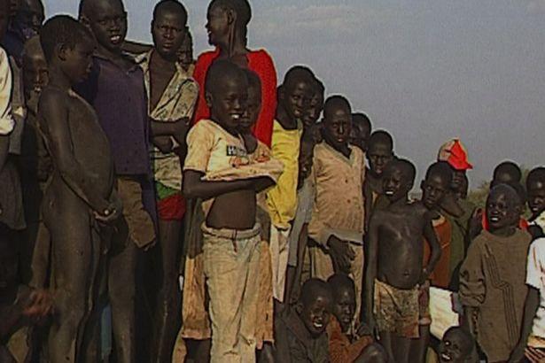  Emmanuel Jal, in the middle pulling up his white t-shirt, with other so-called Lost Boys