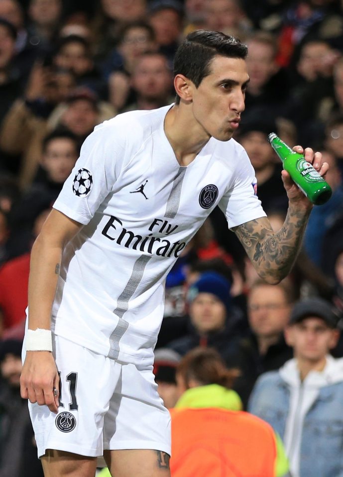  Angel Di Maria pretends to drink from a beer bottle that was thrown at him from the stands