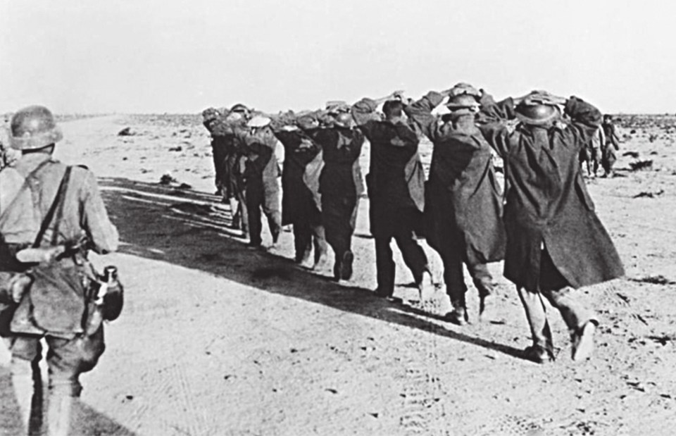  British prisoners captured during the fall of Tobruk, Libya are escorted away by members of the Afrika Korps under the beating sun