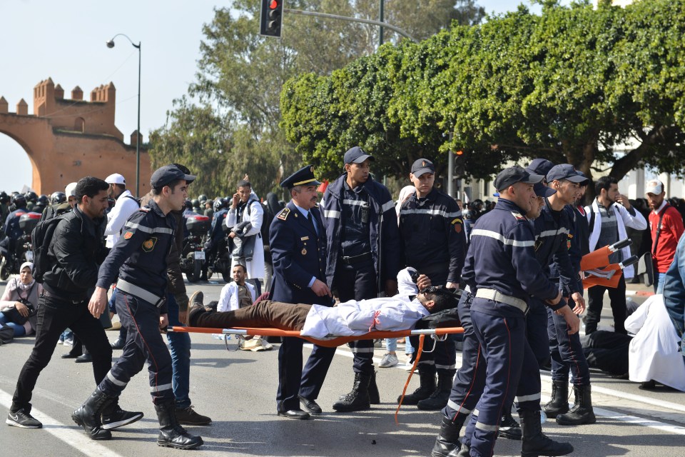  An injured protestor is escorted away by security forces