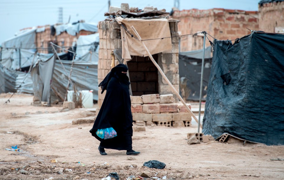 A displaced Syrian woman walks through Begum’s squalid Syrian refugee camp