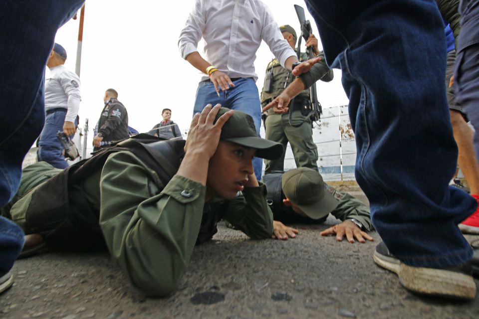  Two Venezuelan soldiers lie on the ground as they are detained by Colombian police after driving into Colombia in an armor car from the Venezuelan side of Simon Bolivar International bridge in Cucuta today