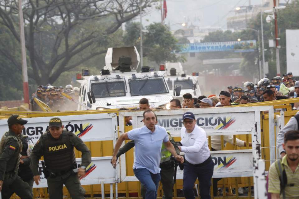  Civilians run as armed vehicles charge towards protesters on the blockade at the Colombian border