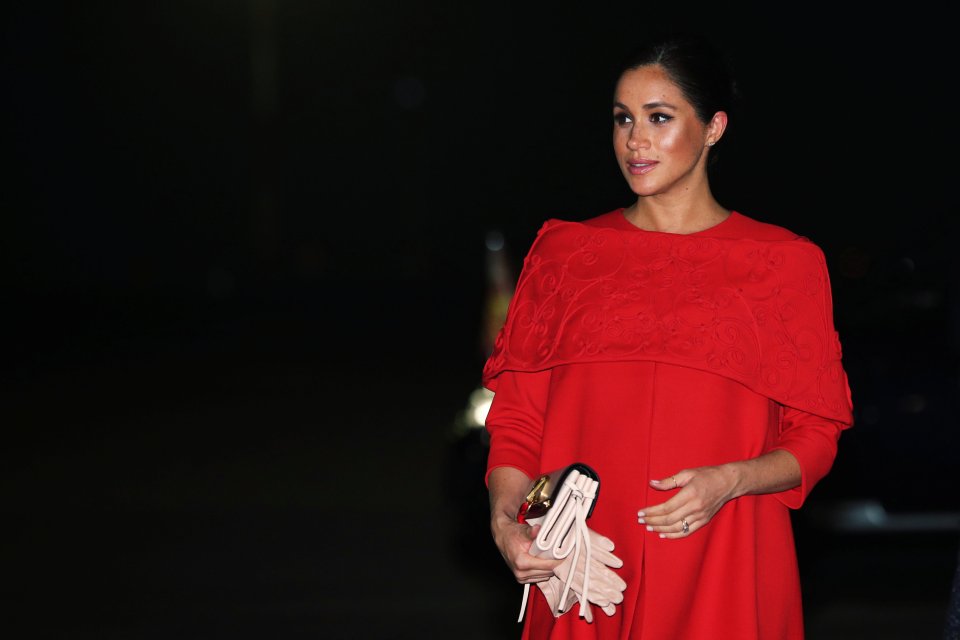  Meghan cradled her baby bump after stepping off the plane