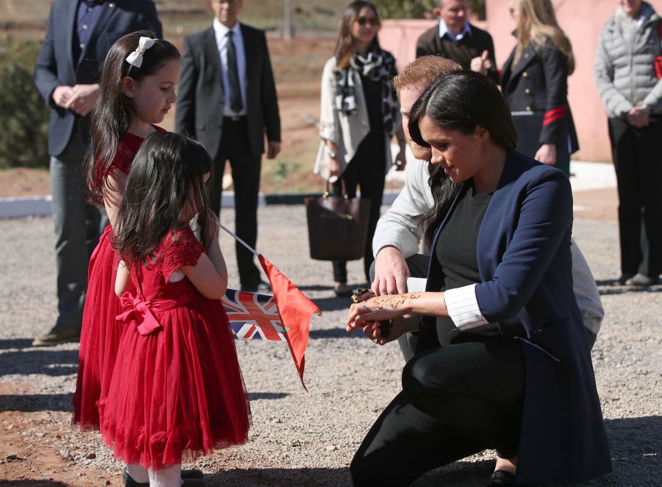  Meghan Markle shows her henna tattoo to Rania, five, and Rayhanna, two, in Morocco today