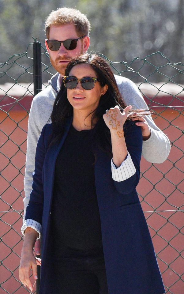  Harry places a protective hand on Meghan's shoulder as they watch a football match