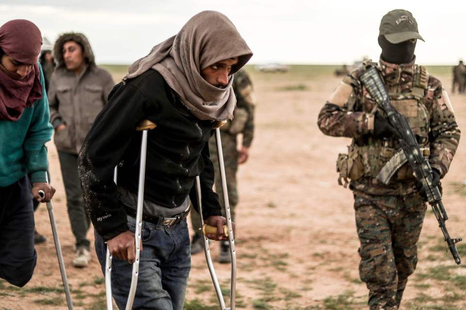  Men suspected of being Islamic State fighters wait to be searched by members of the SDF