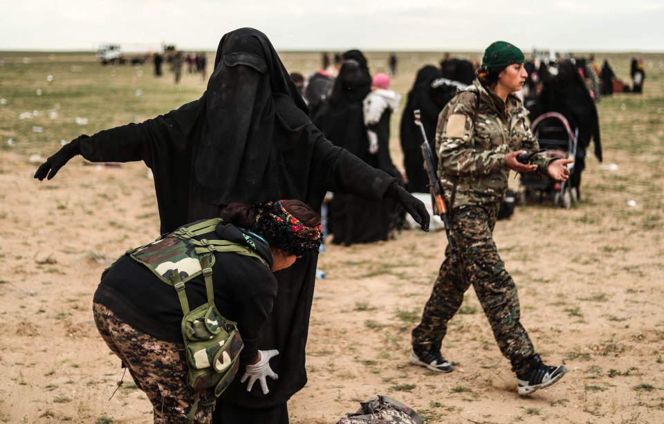  An SDF soldier searches a woman after she left the ISIS group's holdout of Baghouz, in Syria's northern Deir Ezzor province