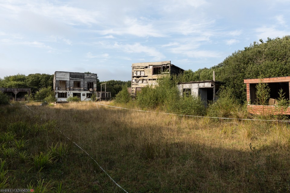 The grass has overgrown into many of the empty structures still left on the site